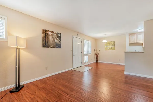 a view of an empty room with wooden floor and a window