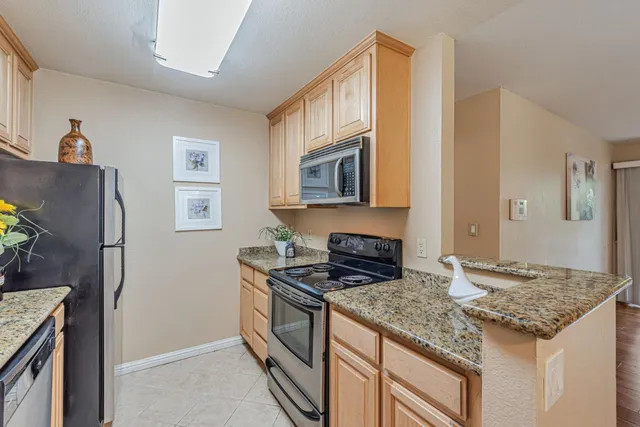 a kitchen with granite countertop cabinets stainless steel appliances and a counter space