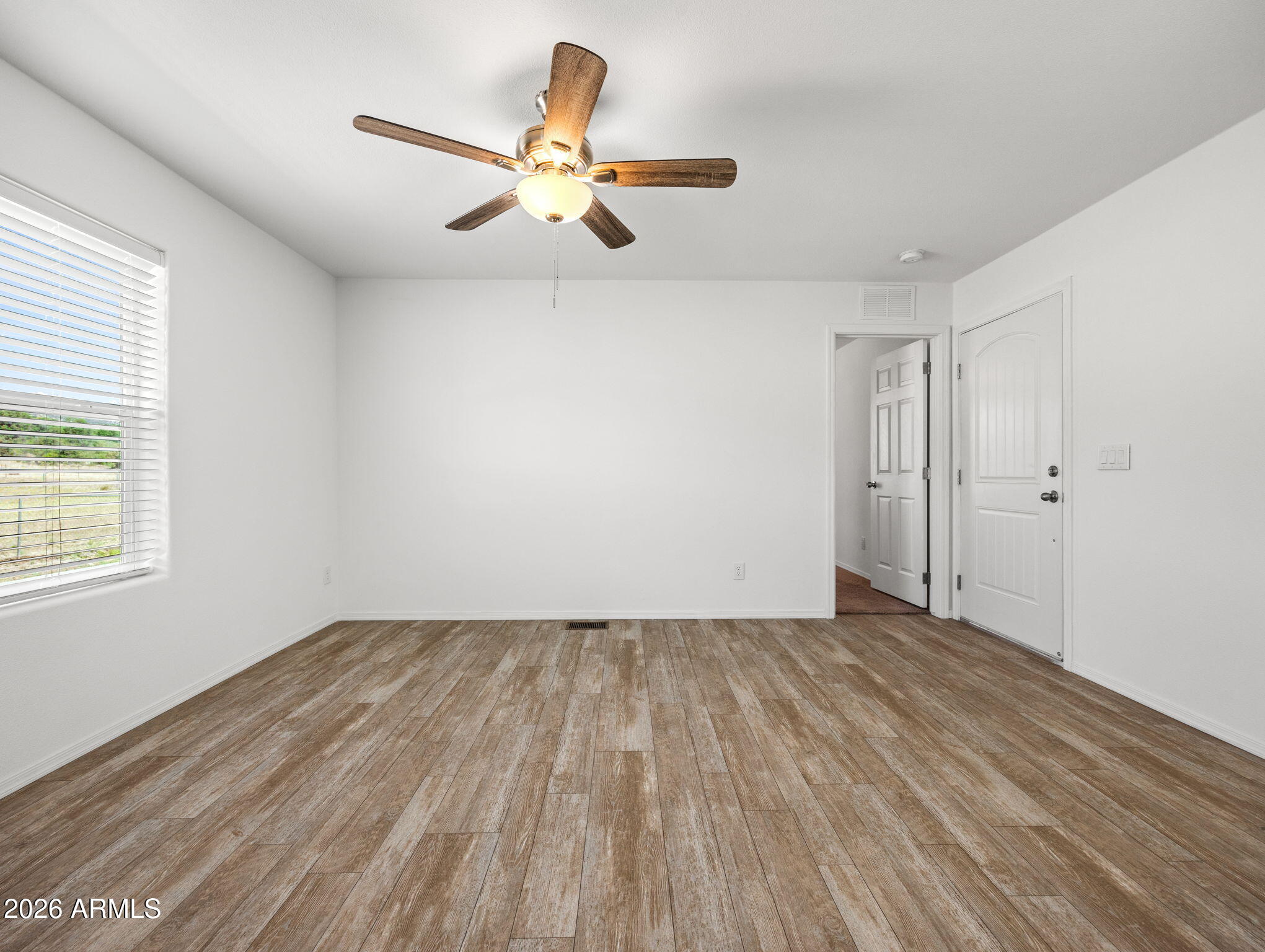 18296 Frontier Road Peeples Valley, AZ 86332 - Photo 19 of 44 an empty room with wooden floor fan and windows