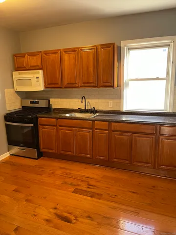a kitchen with stainless steel appliances granite countertop a sink cabinets and wooden floor