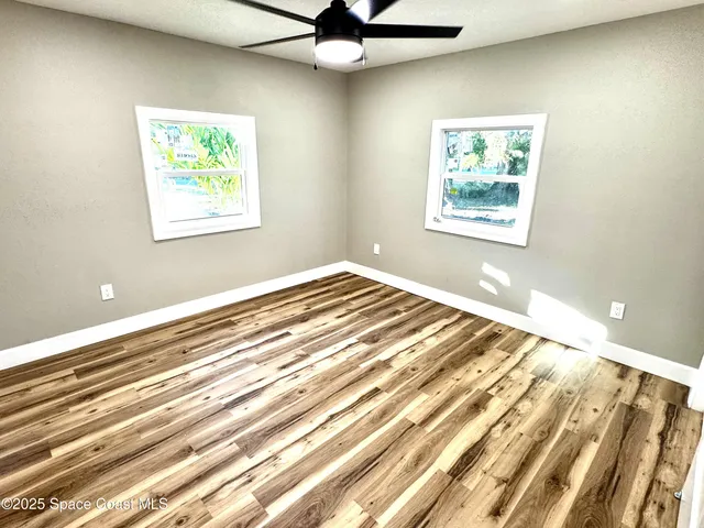 a view of a bedroom with wooden floor and a window