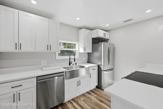 a kitchen with a sink a refrigerator and white cabinets