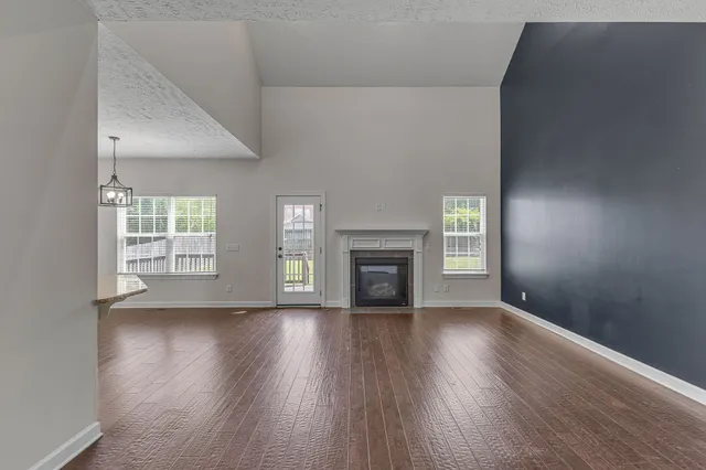 an empty room with wooden floor fireplace and windows