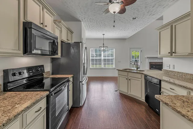 a kitchen with stainless steel appliances granite countertop a sink and cabinets with wooden floor