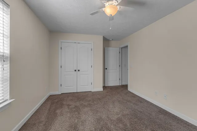 an empty room with a window and ceiling fan