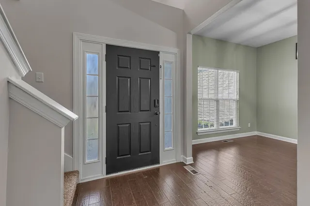 an empty room with wooden floor chandelier and windows