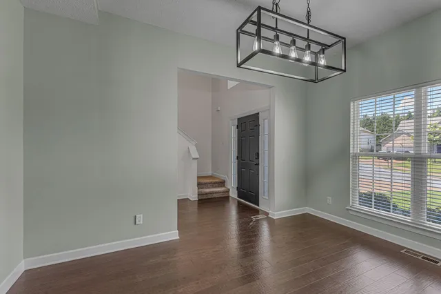 an empty room with wooden floor fireplace and windows
