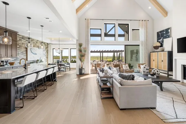 a very nice looking living room with a large window a rug kitchen view and a chandelier