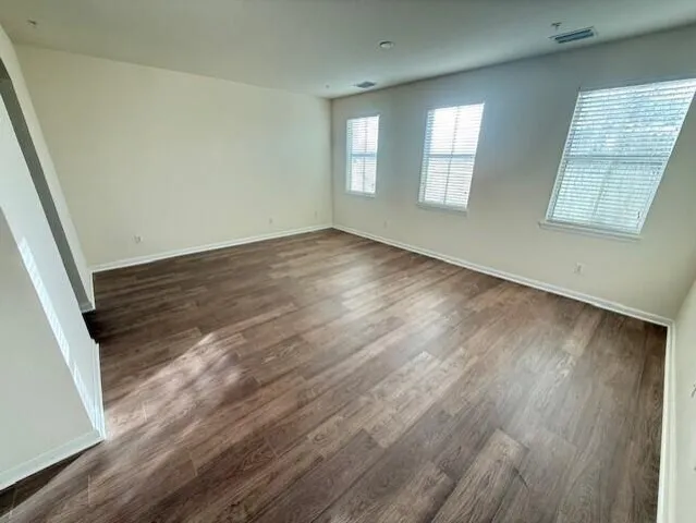 an empty room with wooden floor and windows
