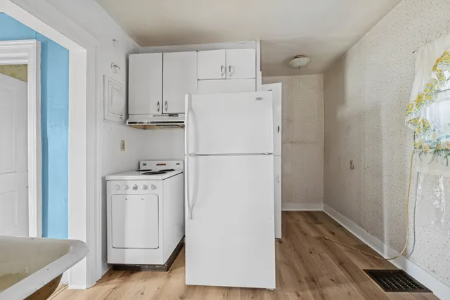 a white refrigerator freezer and a wooden floor
