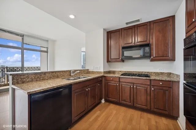 a kitchen with stainless steel appliances granite countertop wooden cabinets and a stove top oven