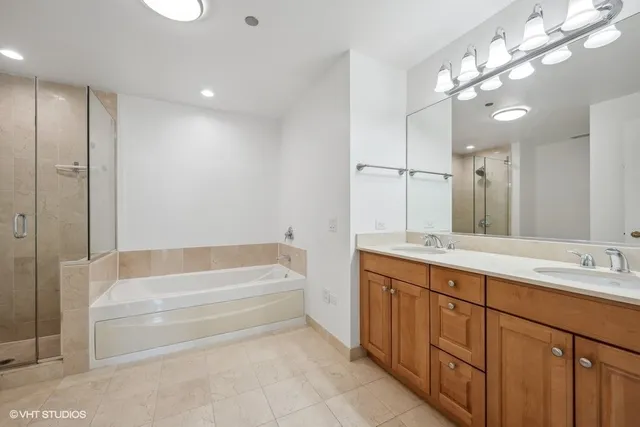 a bathroom with a tub a sink double vanity and a mirror