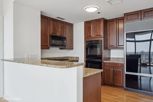 a kitchen with granite countertop wooden cabinets a stove top oven and stainless steel appliances