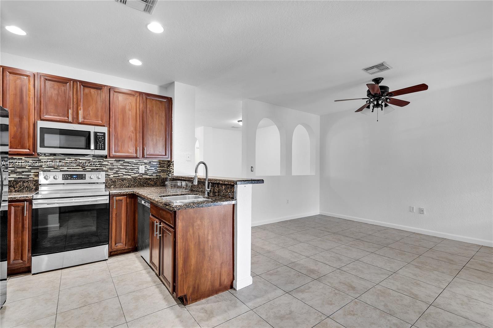 14044 Southwest 273rd Lane, Unit 14044 Homestead, FL 33032 - Photo 11 of 44 a kitchen with a stove a sink and a microwave