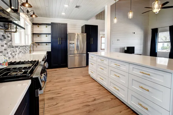 a kitchen with stainless steel appliances kitchen island granite countertop a stove and a refrigerator