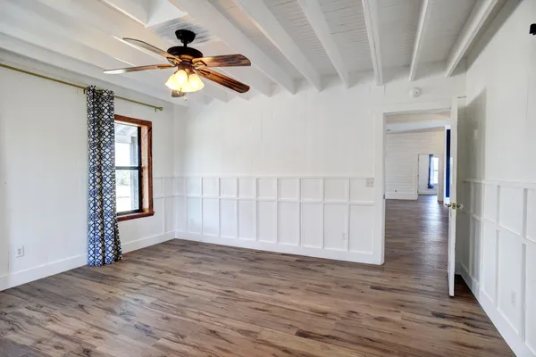 a view of an empty room with a window and wooden floor
