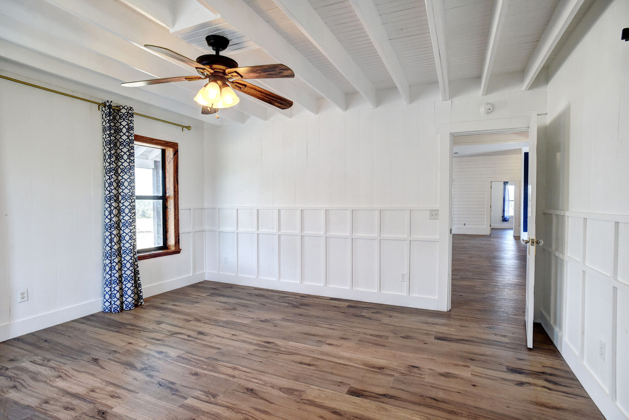4165 Pin Oak Road Muldoon, TX 78949 - Photo 15 of 44 Unfurnished room with a decorative wall, dark wood finished floors, ceiling fan, a wainscoted wall, and beamed ceiling