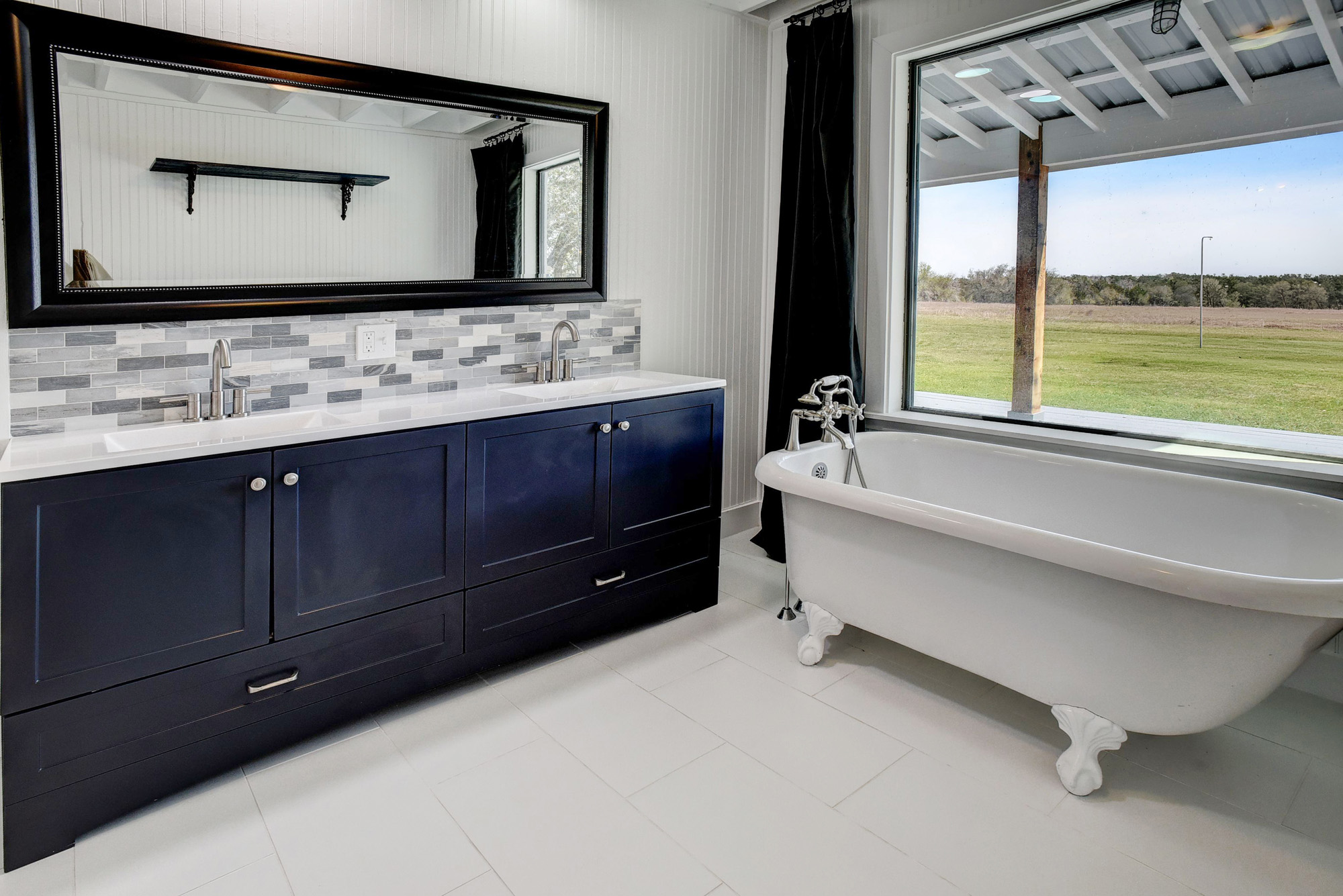 4165 Pin Oak Road Muldoon, TX 78949 - Photo 18 of 44 Bathroom featuring double vanity, decorative backsplash, a freestanding tub, and light tile patterned floors