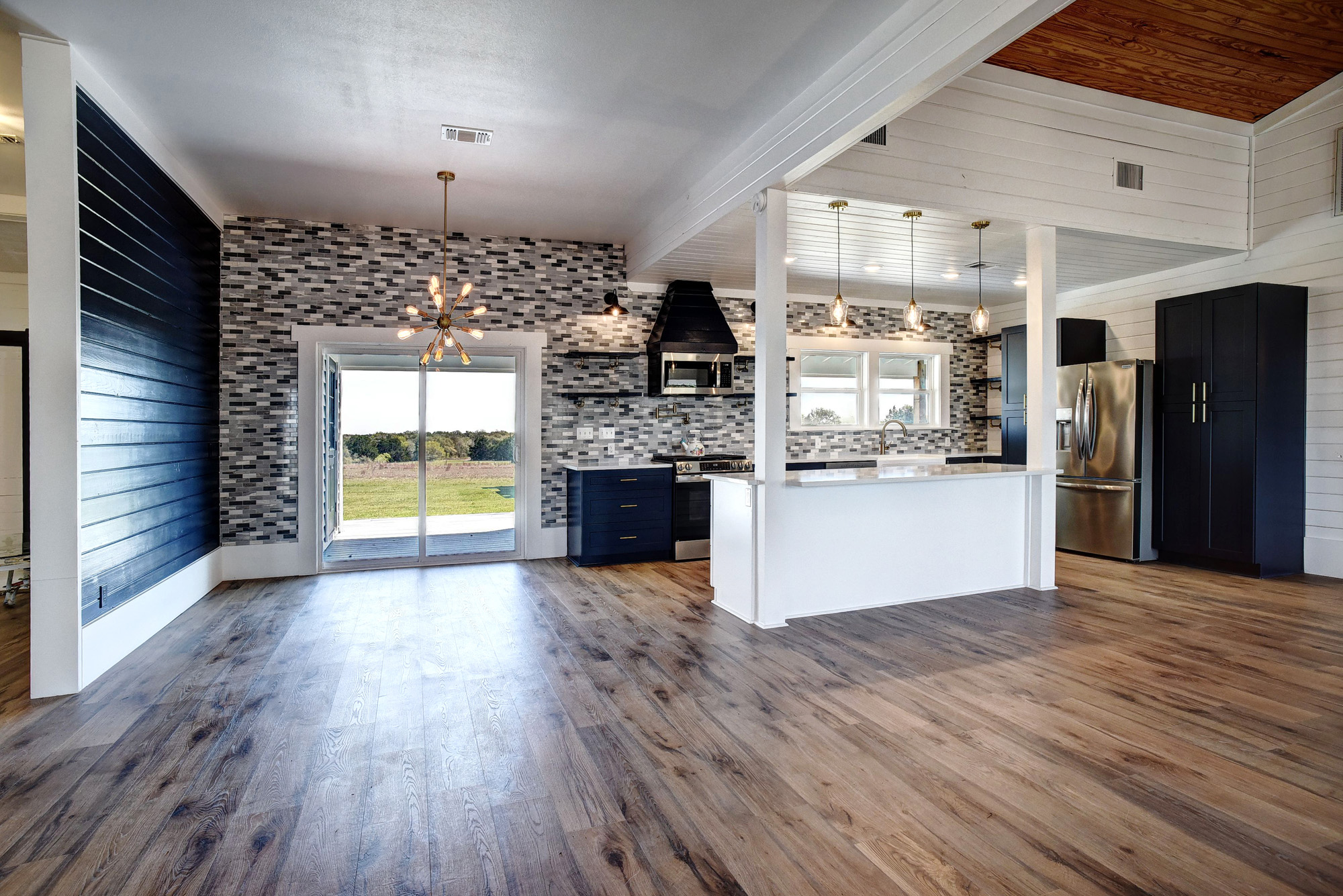 4165 Pin Oak Road Muldoon, TX 78949 - Photo 10 of 44 Kitchen featuring stainless steel appliances, dark wood-style flooring, a center island, healthy amount of natural light, and wood walls