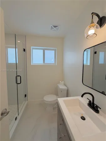 a bathroom with a sink a toilet and shower