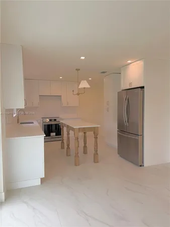 a kitchen with stainless steel appliances granite countertop a refrigerator a sink a stove and white cabinets