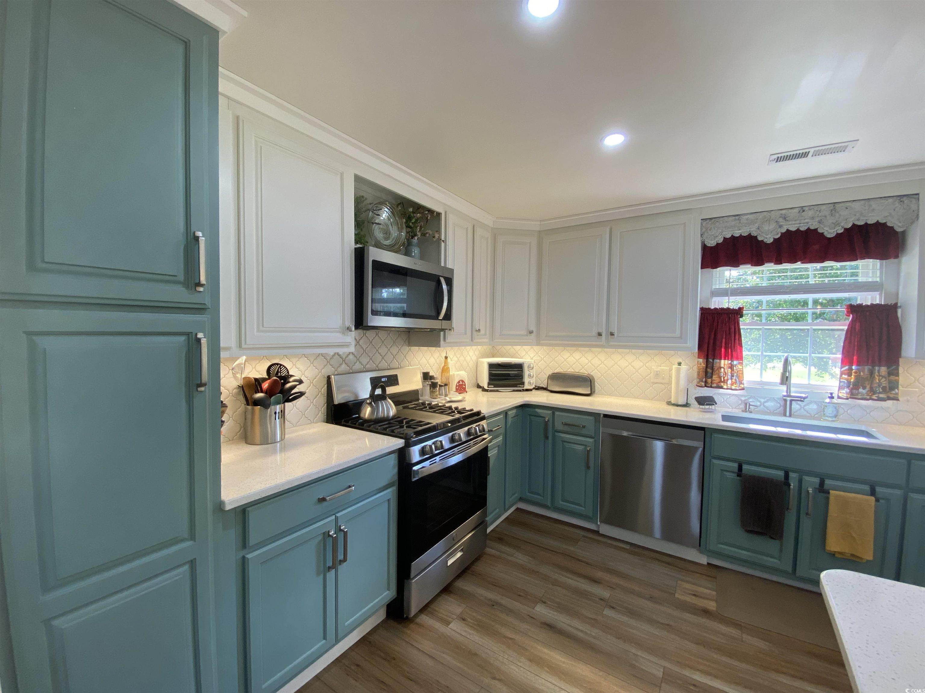 2593 Long Ave Extension Conway, SC 29526 - Photo 22 of 40 Kitchen featuring appliances with stainless steel finishes, backsplash, dark wood-style flooring, white cabinets, and recessed lighting
