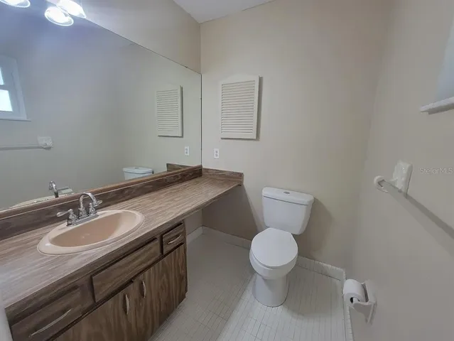 a bathroom with a granite countertop toilet sink and mirror