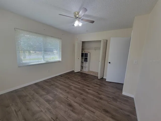 a view of an empty room with a window and a kitchen