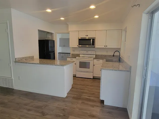 a kitchen with stainless steel appliances granite countertop a refrigerator a stove top oven a sink and dishwasher