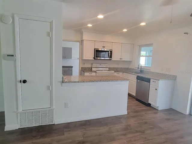a kitchen with kitchen island a sink stainless steel appliances and white cabinets