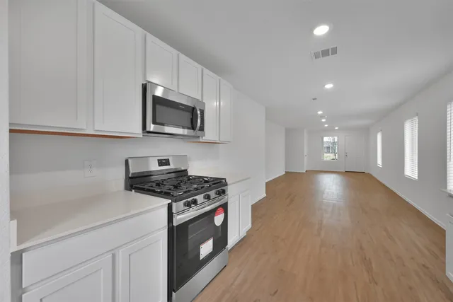 a kitchen with granite countertop a stove and a wooden floor