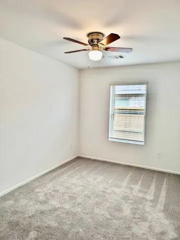 an empty room with a ceiling fan and window
