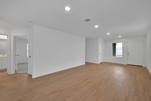 a view of an empty room with wooden floor and closet