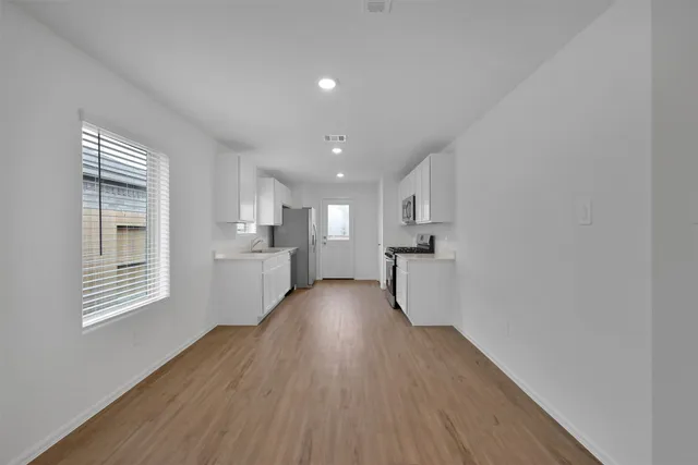 a view of a kitchen with wooden floor and a window