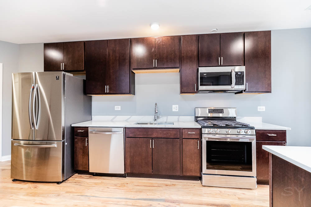 1411 East 67th Place, Unit 2W Chicago, IL 60637 - Photo 5 of 14 a kitchen with kitchen island a counter space a sink and stainless steel appliances