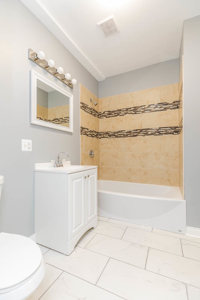 1411 East 67th Place, Unit 2W Chicago, IL 60637 - Photo 10 of 14 a bathroom with a bathtub a toilet a sink and mirror
