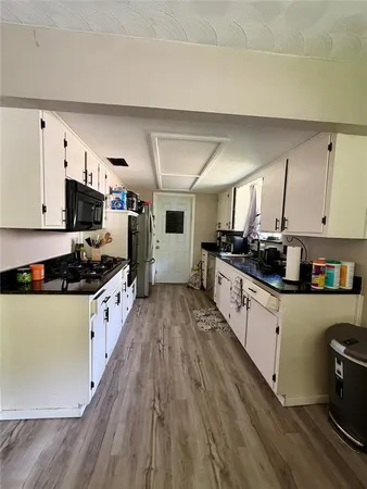 a kitchen with granite countertop a stove top oven a sink dishwasher and a refrigerator with wooden floor