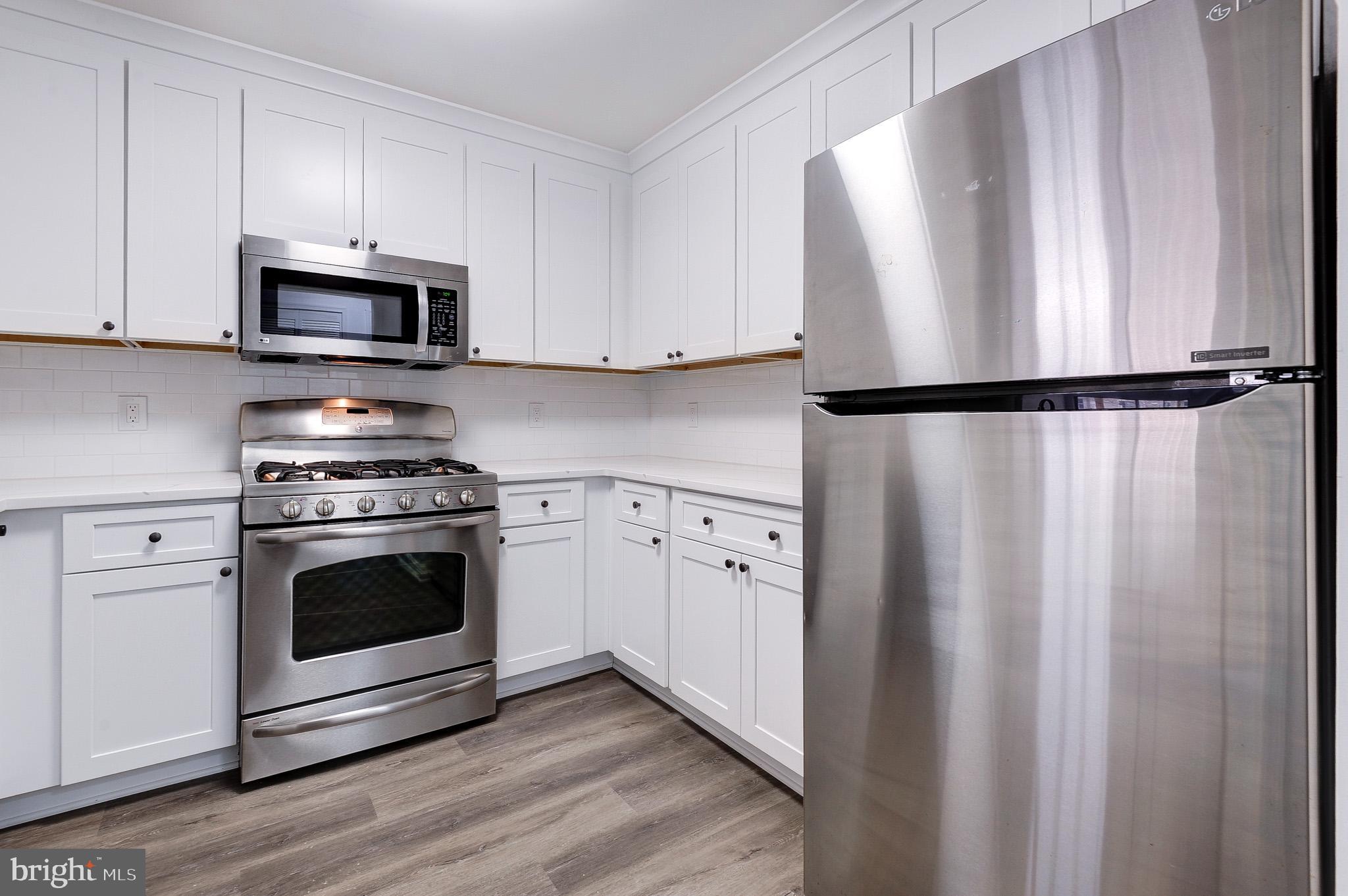 20600 Cornstalk Terrace, Unit 202 Ashburn, VA 20147 - Photo 11 of 31 a white refrigerator freezer and a stove sitting inside of a kitchen with granite countertop stainless steel appliances