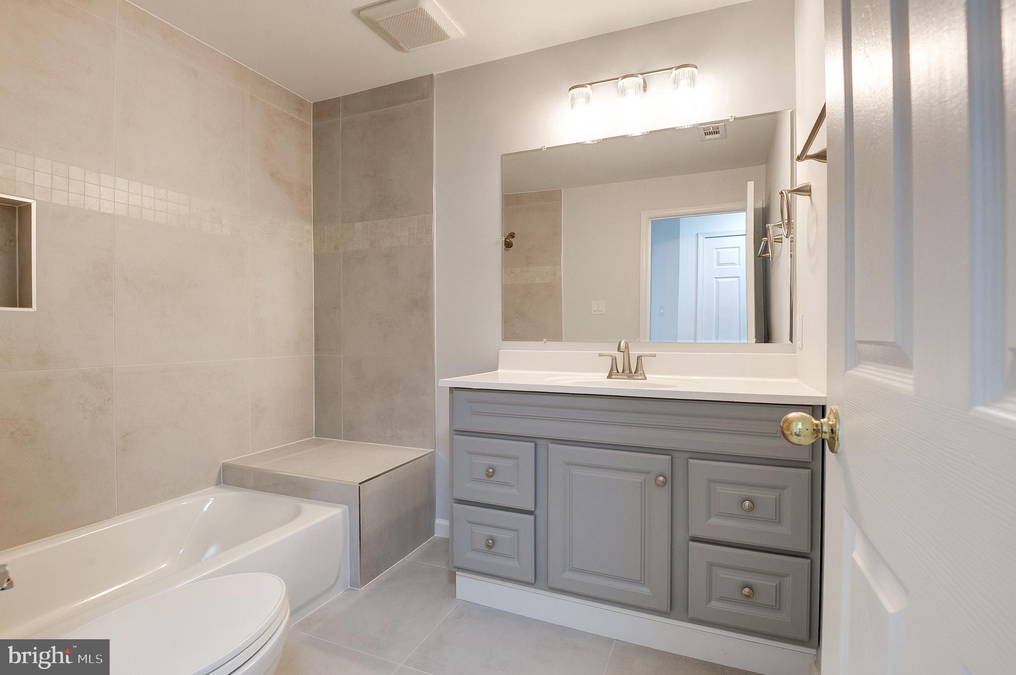 20600 Cornstalk Terrace, Unit 202 Ashburn, VA 20147 - Photo 22 of 31 a bathroom with a granite countertop toilet a sink and bathtub