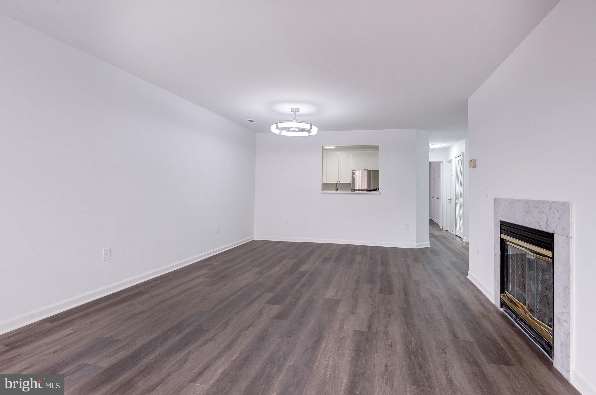 20600 Cornstalk Terrace, Unit 202 Ashburn, VA 20147 - Photo 10 of 31 an empty room with wooden floor fireplace and windows