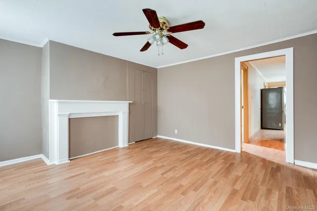 a view of empty room with wooden floor and ceiling fan