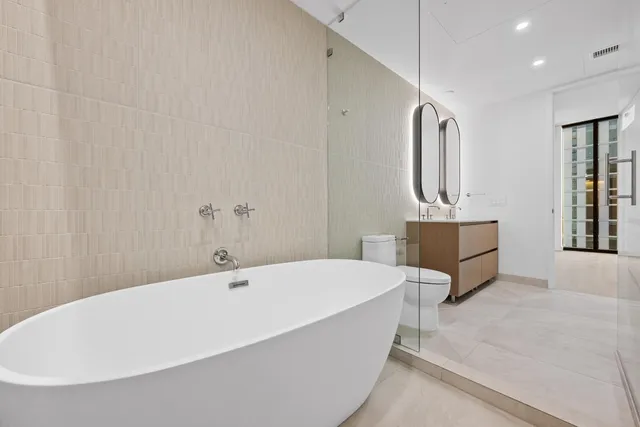 a white tub sitting in a spacious bathroom next to a window