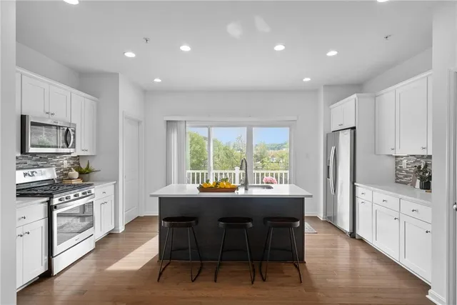 a kitchen with stainless steel appliances granite countertop a table chairs sink refrigerator and cabinets