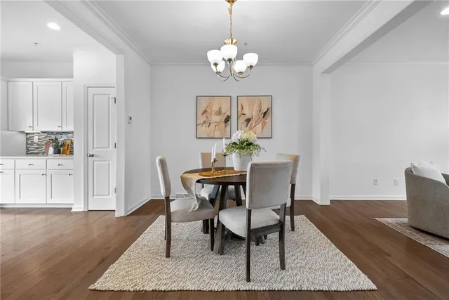 a dining room with wooden floor a chandelier a wooden table and chairs