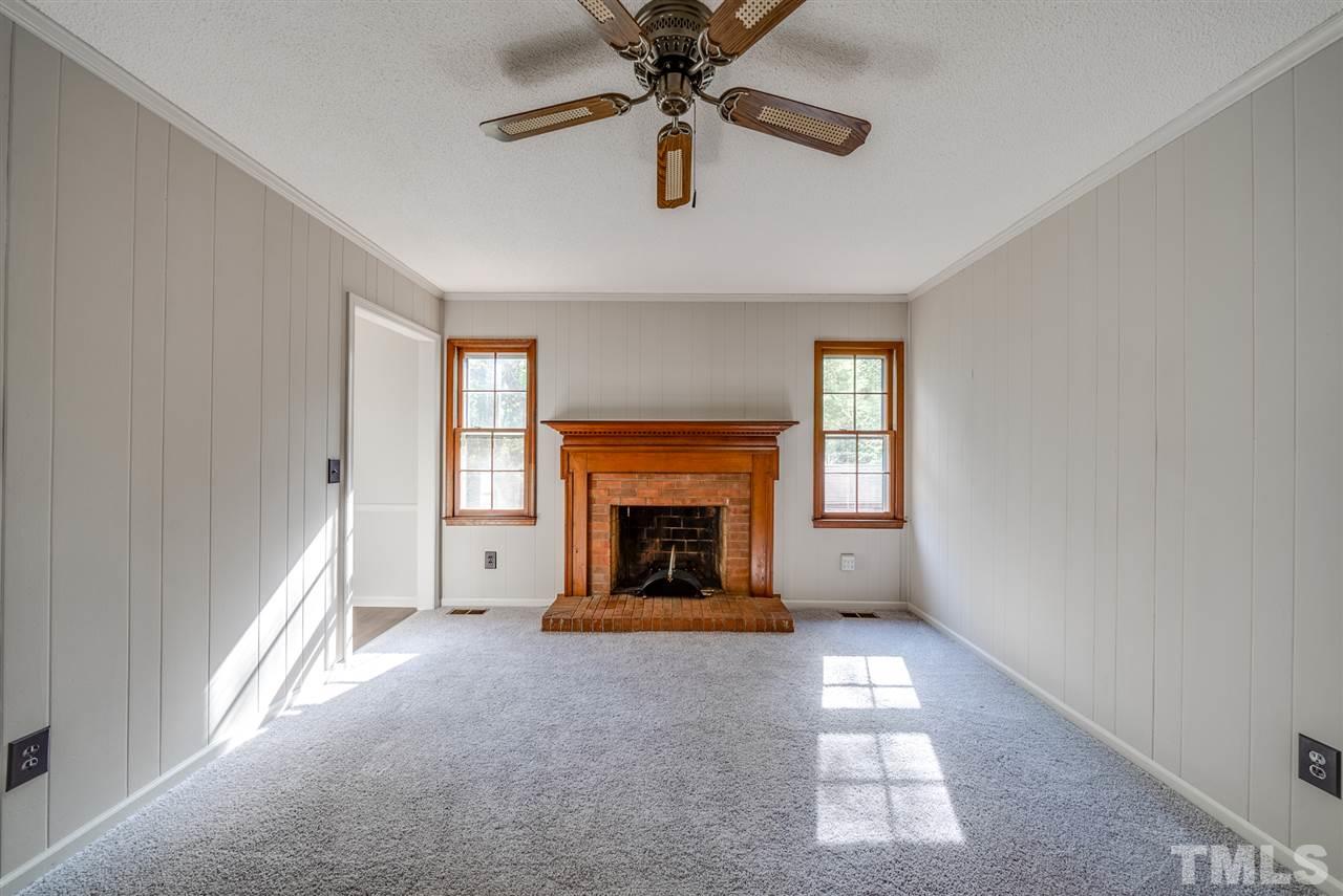 7408 Mine Shaft Road Raleigh, NC 27615 - Photo 6 of 20 a view of a livingroom with a fireplace a ceiling fan and windows