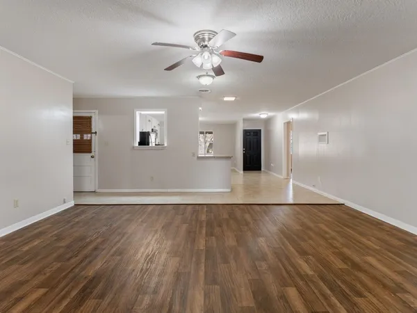 a view of an empty room with wooden floor and a ceiling fan