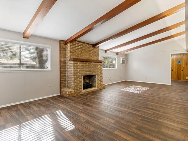 a view of empty room with wooden floor and fireplace