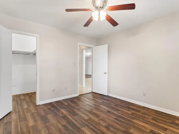 an empty room with wooden floor chandelier fan and closet area