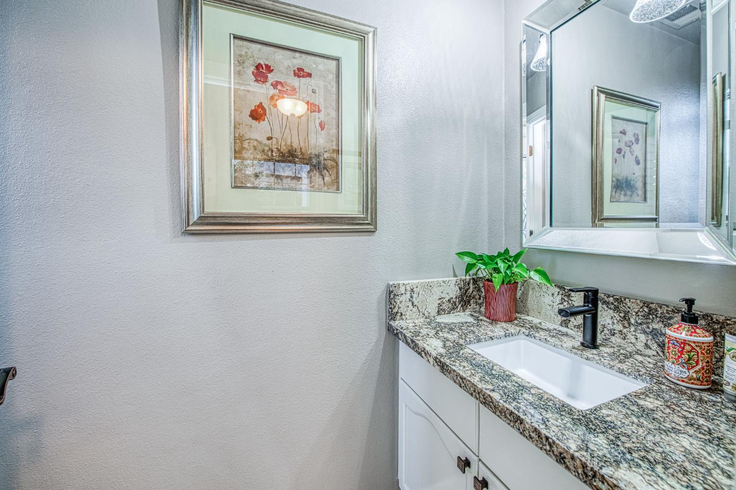 3077 West Pembrook Loop Fresno, CA 93711 - Photo 18 of 56 a bathroom with a granite countertop sink a mirror and vanity
