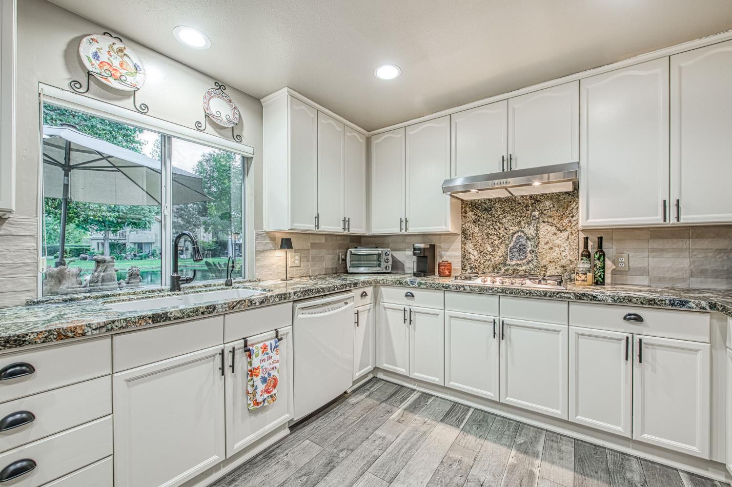 3077 West Pembrook Loop Fresno, CA 93711 - Photo 33 of 56 a kitchen that has a lot of white cabinets and a wooden floor